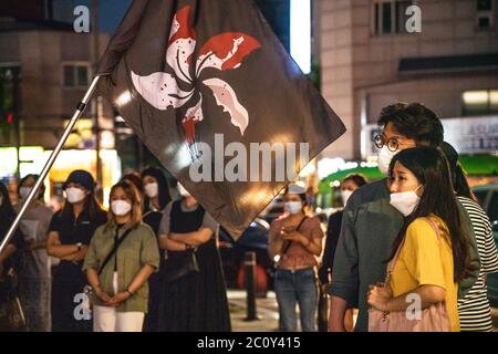 Seoul, Südkorea. Juni 2020. Demonstranten mit Schutzmasken sehen sich während der Demonstration eine Videovorführung an. Anlässlich des 1. Jahrestages der Proteste gegen Chinas Sicherheitsgesetze veranstalteten die Menschen in Seoul, Südkorea, eine Protestveranstaltung und eine Videovorführung. Kredit: SOPA Images Limited/Alamy Live Nachrichten Stockfoto