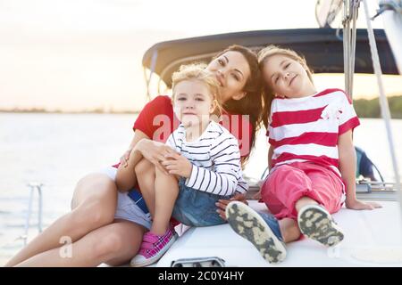 Schöne glückliche Mutter mit zwei Töchtern, die tolle Zeit auf der Yacht haben Stockfoto