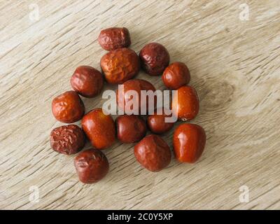 Getrocknete Unabi-Früchte oder Jujube isoliert auf Holzgrund. Ziziphus jujujuba, allgemein Jujube genannt, rotes Datum, chinesisches Datum. Nahaufnahme. Stockfoto