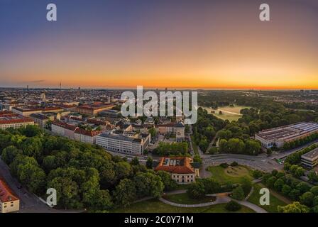 Weite Sicht über München am Morgen, wo der beliebte grüne Park namens englischer Garten von Nebel bedeckt ist. Panorama-Sonnenaufgang von einer Drohne. Stockfoto