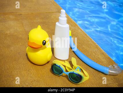 Sonnencreme, Schnorchel, Schutzbrille und gelbe Gummiente Stockfoto
