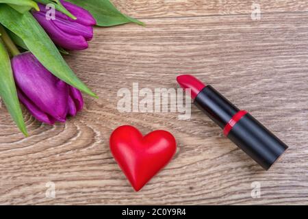 Lippenstift, rote Herzen und Tulpen auf einer hölzernen Hintergrund Stockfoto