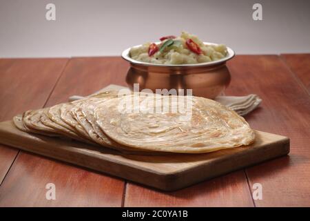 Hausgemachtes Kerala Parotta/Porotta/Paratha/geschichtetes Flachbrot mit Weizen, beliebt in Südindien, serviert in einem Holzbrett mit braunem Holzhintergrund Stockfoto