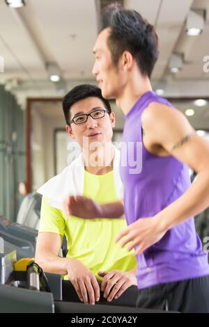 Junge asiatische Männer und trainieren Sie im modernen Fitnessraum Stockfoto