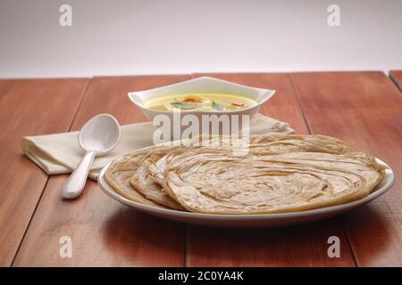 Hausgemachtes Kerala Parotta/Porotta/Paratha/geschichtetes Flachbrot mit Weizen, beliebt in Südindien, serviert in einem Holzbrett mit braunem Holzhintergrund Stockfoto