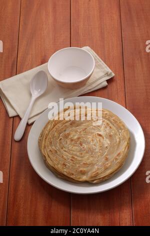 Hausgemachtes Kerala Parotta/Porotta/Paratha/geschichtetes Flachbrot mit Weizen, beliebt in Südindien, serviert in einem Holzbrett mit braunem Holzhintergrund Stockfoto