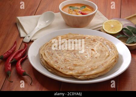 Hausgemachtes Kerala Parotta/Porotta/Paratha/geschichtetes Flachbrot mit Weizen, beliebt in Südindien, serviert in einem Holzbrett mit braunem Holzhintergrund Stockfoto