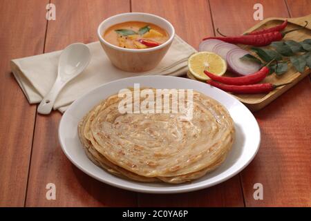 Hausgemachtes Kerala Parotta/Porotta/Paratha/geschichtetes Flachbrot mit Weizen, beliebt in Südindien, serviert in einem Holzbrett mit braunem Holzhintergrund Stockfoto