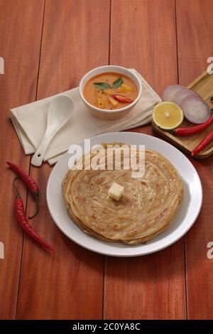 Hausgemachtes Kerala Parotta/Porotta/Paratha/geschichtetes Flachbrot mit Weizen, beliebt in Südindien, serviert in einem Holzbrett mit braunem Holzhintergrund Stockfoto