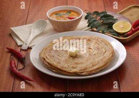 Hausgemachtes Kerala Parotta/Porotta/Paratha/geschichtetes Flachbrot mit Weizen, beliebt in Südindien, serviert in einem Holzbrett mit braunem Holzhintergrund Stockfoto