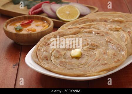 Hausgemachtes Kerala Parotta/Porotta/Paratha/geschichtetes Flachbrot mit Weizen, beliebt in Südindien, serviert in einem Holzbrett mit braunem Holzhintergrund Stockfoto