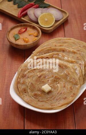 Hausgemachtes Kerala Parotta/Porotta/Paratha/geschichtetes Flachbrot mit Weizen, beliebt in Südindien, serviert in einem Holzbrett mit braunem Holzhintergrund Stockfoto