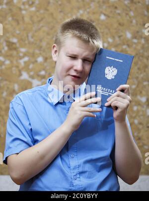 Schuljunge mit dem Zertifikat über den Abschluss der Ausbildung in der Schule , aufgeregt von Abschied mit sch Stockfoto