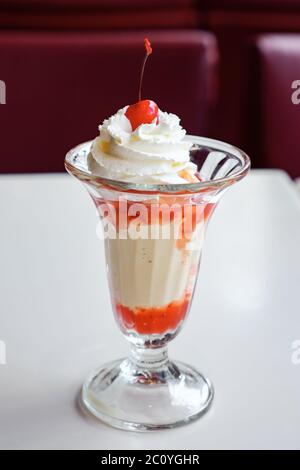 Eis mit Erdbeersirup und Schlagsahne in einem Glas. Stockfoto