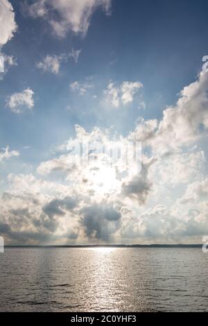 Die Sonne scheint dramatisch durch die Wolken über dem Meer Stockfoto