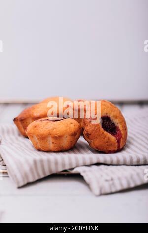 Hausgemachte Erdbeermuffins auf Holztablett mit weiß karierter Serviette unterordentlich. Stockfoto