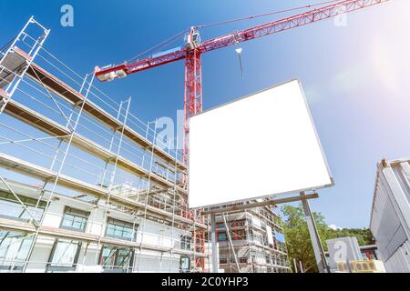 Weiße Plakatwand vor der Baustelle mit Gerüst und Kran Stockfoto