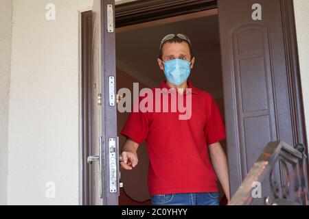 Ein Klient in einer medizinischen Maske öffnete die Tür, um Essen zu liefern Stockfoto