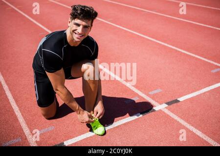 Porträt von männlichen Athleten auf der Laufstrecke ihre Schnürsenkel zu binden Stockfoto