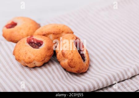 Hausgemachte Erdbeermuffins auf Holztablett mit weiß karierter Serviette unterordentlich. Stockfoto