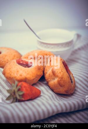 Erdbeermuffin mit frischen Erdbeeren in einem Schnitt auf einem weißen Holztisch. Stockfoto