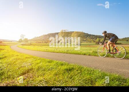 Radfahrer auf einem Rennrad in landschaftlich reizvolle Herbstlandschaft Reiten in den Sonnenuntergang Stockfoto