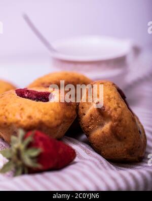 Erdbeermuffin mit frischen Erdbeeren in einem Schnitt auf einem weißen Holztisch. Stockfoto