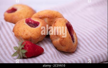 Erdbeermuffin mit frischen Erdbeeren in einem Schnitt auf einem weißen Holztisch. Stockfoto
