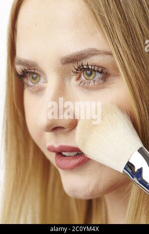 Blonde junge Frau verwendet Pinsel zu Pulver Stockfoto