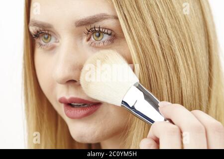 Blonde junge Frau verwendet Pinsel zu Pulver Stockfoto