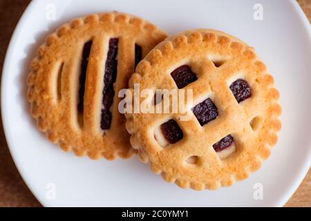 Kekse mit Marmelade in Untertasse auf Tischplatte anzeigen Stockfoto