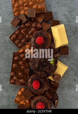 Auswahl an weißer, dunkler und Milchschokolade mit Nüssen, Muffins, Donuts Stockfoto