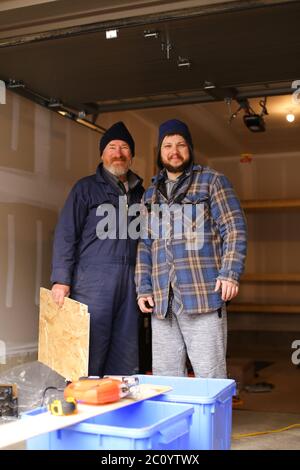 Zwei Tischler stehen in der Werkstatt, Puzzle und Holz auf dem Tisch. Stockfoto