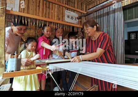 (200613) -- HUZHOU, 13. Juni 2020 (Xinhua) -- Wang Yishi (1. L) und seine Frau Ji Jinmei (1. R) stellen Kindern die Technik der Seidenherstellung in seinem Jili Seidenmuseum in der Stadt Huzhou, Ostchina Zhejiang Provinz, 12. Juni 2020 vor. Die Seide von Jili, die im Dorf Jili in Huzhou hergestellt wird, ist für ihre hohe Qualität bekannt. Es wurde als Material für die Herstellung von Seilen für chinesische Kaiser seit der Mitte der Ming-Dynastie (1368-1644) bezeichnet. 2011 wurde die Herstellung der Seide als eines der nationalen immateriellen Kulturgüter aufgeführt. Es ist weltweit bekannt seit 1851, als Jili Seide die Firs gewann Stockfoto