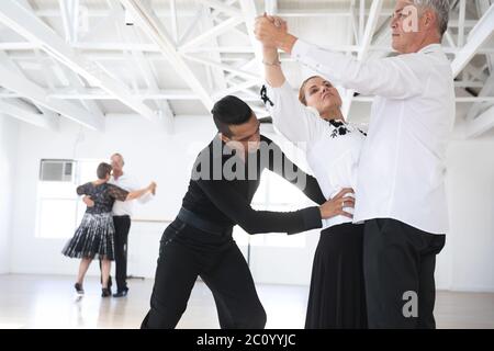 Mixed Race Tanzlehrer hilft seinem Ballsaal Tanzkurs Stockfoto