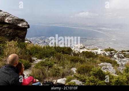KAPSTADT - 12. NOVEMBER 2015. Mann und Frau blicken auf Kapstadt vom Aussichtspunkt auf dem Tafelberg. Neblig bewölkt, Tourist Stockfoto