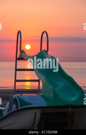 Tretboot am Strand am Morgen während der erstaunlichen Ozean Sonnenaufgang in Rivazzurra (Rimini / Italien) Stockfoto