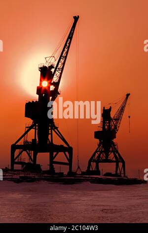 Silhouetten Krane Frachtschiff am Ufer des Baikalsees im Winter bei Sonnenuntergang. Stockfoto