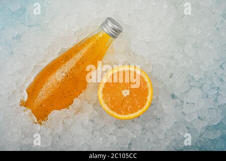 Nahaufnahme eine Glasflasche mit kaltem Orangensaft Cocktail-Drink mit Chiasamen und halb geschnittener Orange auf zerkleinertem Eis im Einzelhandel, hoher Angl Stockfoto