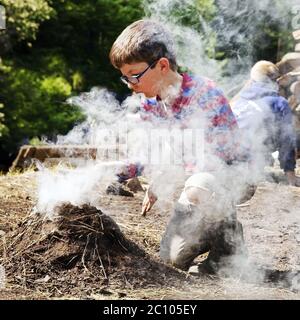 Jungen mit Rauchen Holzkohle Pile, Ennepetal, Ruhrgebiet, Nordrhein-Westfalen, Deutschland Stockfoto