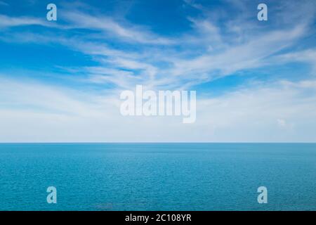 Weiße flauschige Wolken und türkisfarbenes Meer auf blauem Himmel