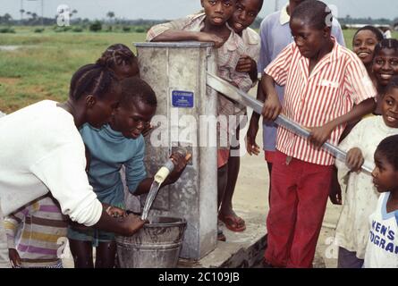 Kinder im Flüchtlingslager außerhalb von Monrovia beziehen frisches Trinkwasser aus dem Brunnen, Liberia 1993 Stockfoto