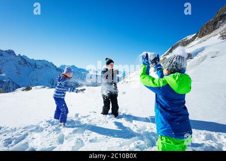Gruppe von Kindern spielen Schneeballschlacht Blick hinter Jungen Schulter mit Schneebällen und Schnee in der Luft über Berge Stockfoto