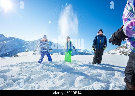 Gruppe von glücklichen Kindern spielen Schneeballschlacht Schneewerfen über Berge Gipfel in lustiges Spiel Stockfoto
