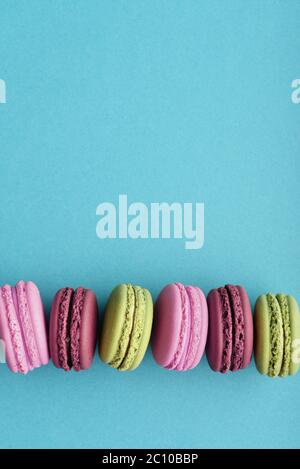 Reihe von bunten französisch Macarons auf blauem Hintergrund. Draufsicht. Pastellfarben Stockfoto