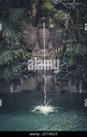 Swimmingpool mit traditionellem, balinesischen Brunnen in Vogelform Stockfoto