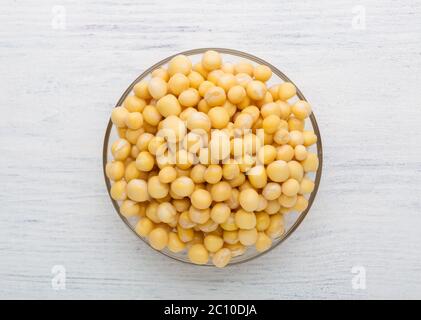 Glasschale mit in Wasser getränkten Erbsen auf einem Holztisch. Draufsicht. Stockfoto