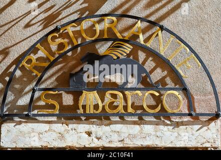 Nahaufnahme des Metallzeichens eines Restaurants mit dem geflügelten Löwen des Hl. Markus, Symbol der Stadt Venedig an einer alten Mauer, Lazise, Verona, Venetien, Italien Stockfoto