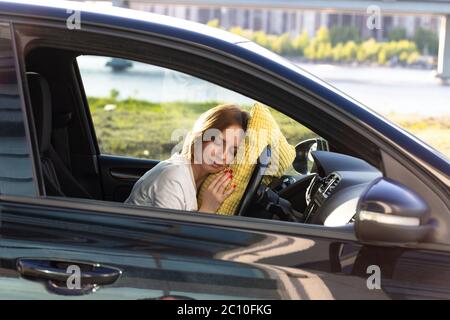 Müde junge Frau Fahrer schlafen auf Kissen auf Lenkrad, Ruhe nach langen Stunden mit dem Auto. Müdigkeit. Schlafentzug. Stockfoto