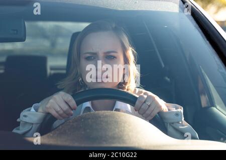 Frau fährt ihr Auto zum ersten Mal, versucht einen Autounfall zu vermeiden, ist sehr nervös und ängstlich, sorgt sich, klammert sich fest am Rad. Unerfahrenwerden Stockfoto